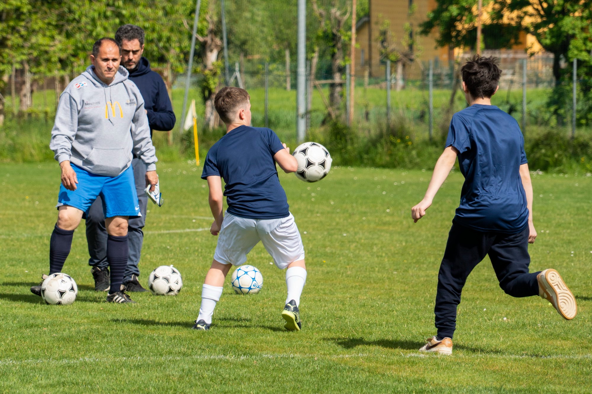 Ragazzi in allenamento sul campo in erba naturale sotto la guida dello staff